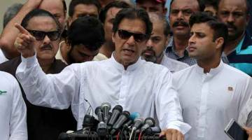 TURUT BERTANDING: Khan (tengah) bercakap di hadapan anggota media selepas membuang undi di balai undian semasa pilihan raya umum berlangsung di Islamabad semalam. — Gambar Reuters