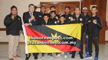 SEMOGA BERJAYA: Ong (dua kiri) dan Norizan (dua kanan) bersama barisan atlet dan pegawai muaythai Sarawak pada majlis penyerahan bendera kelmarin. 