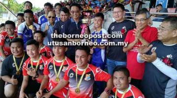 TAHNIAH: Abdul Karim (berdiri, lima kiri) menyampaikan piala kejuaraan kepada SMK Sacred Heart yang mengungguli kategori lelaki bawah 18 tahun kejohanan ragbi 10-sebelah Piala Bro Albinus Edisi Ke-4 di Sibu semalam.