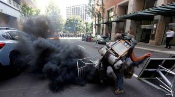 BANTAHAN: Seorang penunjuk perasaan penentang melontar balik kanister gas pemedih mata ke arah polis semasa rali kumpulan Patriot Prayer di Portland, Oregon kelmarin. — Gambar Reuters