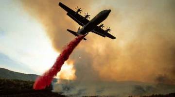 USAHA BERTERUSAN: Pesawat tangki udara menjatuhkan perencat kebakaran ke atas Ranch Fire yang membentuk sebahagian Mendocino Complex Fire yang membakar kawasan di sepanjang Lebuh High Valley dekat Clearlake Oaks, California kelmarin. — Gambar AFP