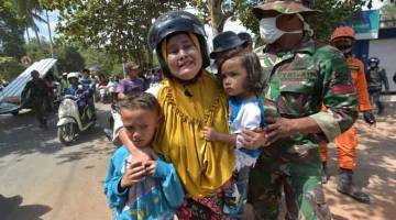 PANIK: Seorang wanita menangis ketakutan sambil memeluk erat dua anaknya sejurus selepas gegaran susulan kuat melanda daerah Tanjung di utara Lombok semalam. — Gambar Adek Berry/AFP