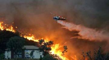 KIAN MARAK: Anggota bomba berusaha memadamkan kebakaran dari atas udara menggunakan helikopter di Lake Elsinore, California. — Gambar AFP