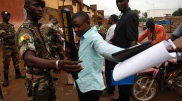 PERIKSA: Anggota tentera Mali menjalankan imbasan badan ketika orang ramai berbaris menunggu giliran di sebuah pusat pengundian di Bamako, semalam. — Gambar Reuters