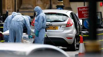 SIASAT: Pegawai forensik memeriksa kereta yang merempuh perintang di luar Bangunan Parlimen di Westminster, London, Britain kelmarin. — Gambar Henry Nicholls/Reuters 