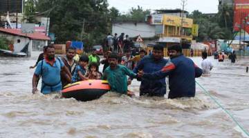 MISI MENYELAMAT: Sukarelawan dan kakitangan penyelamat memindahkan penduduk tempatan ke dalam sebuah bot di kawasan kediaman Aluva di daerah Ernakulam di wilayah Kerala, India kelmarin. — Gambar AFP