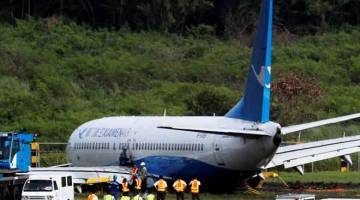 TIADA KEMALANGAN JIWA: Beberapa pekerja cuba mengalihkan Xiamen Air Boeing 737-800 selepas tergelincir dari landasan di Lapangan Terbang Antarabangsa Ninoy Aquino di Paranaque, Metro Manila di Filipina kelmarin. — Gambar Reuters