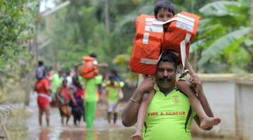 SELAMAT: Anggota bomba dan penyelamat Kerala memikul kanak-kanak mengharungi air banjir                                                                                              semasa operasi menyelamat di kampung Annamanada di Daerah Thrissur, di negeri Kerala,                       selatan India kelmarin. — Gambar Manjunath Kiran/AFP