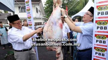 SIMBOLIK: Abang Johari bersama Fadillah melapah daging lembu pada Majlis Korban Aidiladha dan Pengagihan Sumbangan Daging Korban anjuran Pemuda PBB Satok semalam.