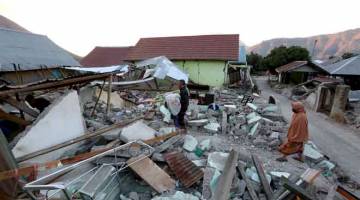 AKIBAT GEMPA: Penduduk         memeriksa rumah mereka  yang roboh di kampung Sembalun di pulau Lombok, Indonesia pada 20 Ogos selepas satu siri gempa bumi direkodkan oleh ahli seismologi sepan-jang 19 Ogos. — Gambar AFP