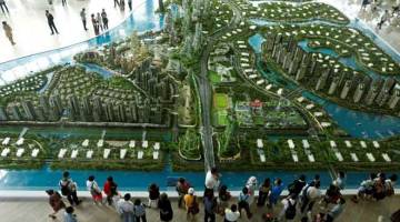 PELABURAN BESAR: Prospek pembeli melihat model projek pembangunan Forest City di ruang pameran Country Gardens di Johor Bahru. — Gambar Reuters