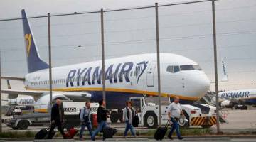 MOGOK: Penumpang berjalan di hadapan pesawat syarikat penerbangan Ryanair, semasa juruterbang dan kru kabin melancarkan mogok terbaharu, di Lapangan Terbang Weeze, berhampiran sempadan Jerman-Belanda semalam. — Gambar Wolfgang Rattay/Reuters 