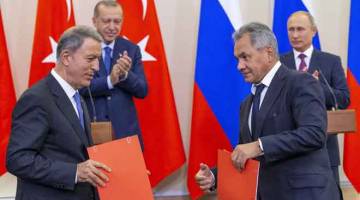 DIPLOMASI: Erdogan dan Putin melihat menteri pertahanan masing-masing Hulusi Akar dan Sergei Shoigu (kanan) bertukar dokumen semasa sidang akhbar susulan rundingan di Sochi, Rusia kelmarin. — Gambar Reuters