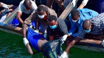 OPERASI MENYELAMAT: Beberapa anggota penyelamat mengangkat mayat seorang lelaki dari air selepas sebuah feri karam di Pulau Ukerewe di Tasik Victoria, Tanzania kelmarin. — Gambar Reuters