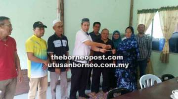 SUMBANGAN: Julani menyampaikan derma kepada salah seorang wakil penerima disaksikan tetamu di Masjid Darul Khairat Bakam, baru-baru ini.