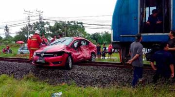 IMPAK KUAT: Anggota bomba mengalihkan kereta yang dirempuh kereta api dekat Petagas, petang semalam. — Gambar Bernama