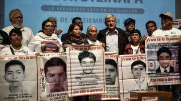 JANJI KEADILAN DITEGAKKAN: Obrador (tengah) bergambar bersama saudara-mara 43 pelajar yang hilang pada 2014, semasa pertemuan di Muzium Memori dan Toleransi di Kota Mexico pada ulang tahun keempat kehilangan mereka kelmarin. — Gambar AFP