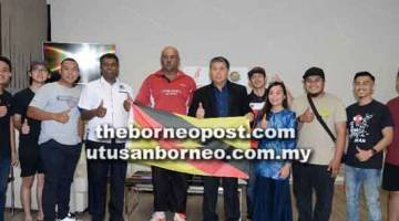 SEMOGA BERJAYA: Ong (lima kanan) menyerahkan bendera Sarawak kepada Ganisan (lima kiri) bersama atlet dan pegawai sukan kabaddi di Kuching semalam.