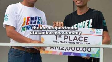 JUARA: Pau (kiri) menyampaikan hadiah kepada pelari terpantas marathon kategori lelaki terbuka 42km, Mohd Jironi.