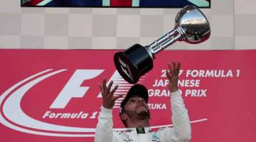 CERIA: Hamilton menjulang trofi kejuaraan ketika meraikan kejayaannya menjuarai Grand Prix Jepun di Litar Suzuka, Jepun pada 8 Oktober lepas. — Gambar AFP