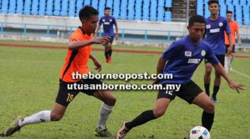 SENGIT: Pemain KSK Satok, Azlan Shah Tahir (kiri) cuba merampas bola daripada pemain Enraz FC, Mohd Isa Abdullah.