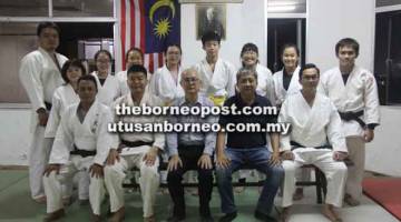 KERJASAMA ERAT: Hiroyuki (duduk tengah) dan Francis (dua kanan) bersama jurulatih dan atlet-atlet judo Sarawak di dojo PJS di Kuching malam kelmarin.