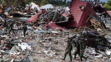 MENCARI MAYAT: Anggota tentera Indonesia meredah puing rumah yang musnah di Petobo, Sulawesi Tengah semalam. — Gambar AFP