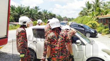 ANGGOTA bomba membuka pintu kereta terbabit bagi mengeluarkan kedua-dua mangsa.