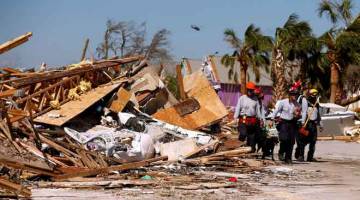 OPERASI MENYELAMAT: Anggota pencari dan penyelamat melintasi runtuhan puing yang ditinggalkan oleh Taufan Michael di Pantai Mexico, Florida kelmarin. — Gambar Reuters