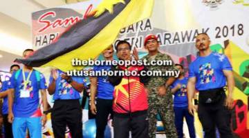 SIMBOLIK: Mohd Nizam mengibarkan bendera Sarawak perasmian Hari Sukan Negara 2018 peringkat negeri di Kota Samarahan semalam.