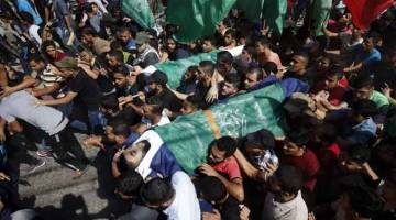 DITANGISI: Penduduk Palestin mengusung mayat al-Taweel (kanan) dan Abu Naim semasa upacara pengebumian tujuh mangsa terbabit di kem Nuseirat, tengah Semenanjung Gaza kelmarin. — Gambar AFP