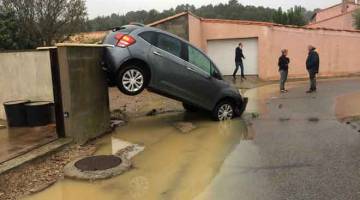 AKIBAT BANJIR: Penduduk berdiri dekat kereta yang dihanyutkan oleh banjir kilat di selatan Perancis kelmarin. — Gambar AFP