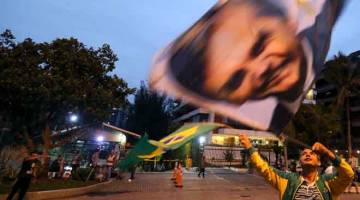 SOKONG: Penyokong me-ngibar bendera tertera wajah Bolsonaro di kawasan kejiranan Barra da Tijuca di Rio de Janeiro pada 5 Oktober lalu. — Gambar Reuters