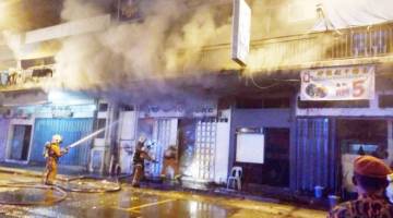 ANGGOTA bomba berusaha memadam api yang mengakibatkan sebuah lot kedai terbakar.