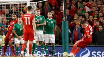 PENYUDAH CANTIK: Wilson (kanan) melepaskan rembatan dari tendangan percuma sebelum menjaringkan gol kemenangan Wales pada perlawanan di Stadium Aviva, Dublin kelmarin. — Gambar Reuters