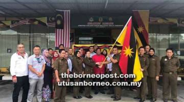 GALAS CABARAN: Agnes (kiri) menyerah bendera kepada Dominic (kanan) sambil disaksikan Paruwadi (tengah) pada majlis ringkas semalam.