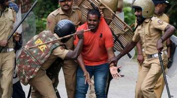 HURU-HARA: Polis India memukul seorang aktivis Hindu yang merayu untuk keselamatan dirinya ketika penunjuk perasaan berhimpun bagi membantah keputusan Mahkamah Agung untuk menarik balik larangan ke atas kemasukan wanita ke sebuah kuil Hindu, di Nilackal dalam negeri selatan Kerala kelmarin. — Gambar AFP