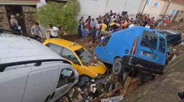 ANGKARA BANJIR: Kereta bertimbun di jalan selepas dihanyutkan oleh banjir di kota Mohamedia dekat Tunis, kelmarin. — Gambar AFP