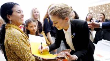 AUTOGRAF: Amber Heard menandatangani autograf dengan coklat Swiss di tangannya, selepas berucap mengenai pengalaman hak asasinya di Geneva pada 22 Oktober lepas. — Gambar Reuters