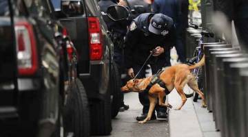 BERWASPADA: Seekor anjing pengesan bom polis dikerahkan di luar Pusat Time Warner selepas sebuah alat letupan dijumpai pagi kelmarin di New York. — Gambar AFP