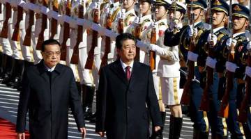 DIBERI PENGHORMATAN: Li (kiri) mengiringi Abe memerika barisan kehormat ketika kedua-dua pemimpin itu menghadiri majlis              sambutan di luar Dewan Agung Rakyat di Beijing, China semalam. — Gambar Reuters