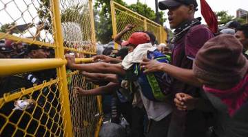 JANGAN MASUK!: Pasukan keselamatan Guatemala (kiri) menghalang migran Honduran sampai ke jambatan sempadan antarabangsa Guatemala-Mexico di Tecun Uman, Guatemala kelmarin. — Gambar AFP