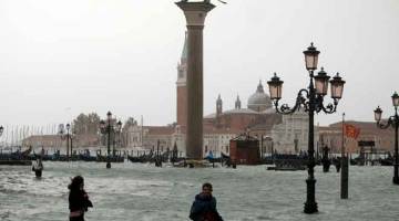 BANJIR: Orang ramai meredah air yang menenggelami Dataran Saint Mark di Venice, kelmarin. — Gambar Reuters