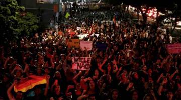 BUKAN DIA!: Pelajar membawa sepanduk bertulis ‘#NotHim’ (Bukan Dia) ketika menyertai perarakan membantah pelantikan                      Bolsonaro sebagai presiden baharu Brazil di Sao Paulo, Brazil kelmarin. — Gambar Reuters