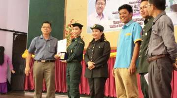 SAIKOM (kiri) menyampaikan anugerah kepada salah seorang pelajar, turut kelihatan Solingkoi (tiga dari kiri).