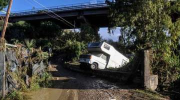 ANGKARA BANJIR: Sebuah kenderaan dilihat terdampar di tepi jalan yang dinaiki banjir kelmarin berhampiran sebuah rumah                       di mana sembilan orang daripada keluarga yang sama mati selepas sebatang sungai melimpah dari tebingnya di Casteldaccia dekat Palermo di pulau Sicily di selatan Itali. — Gambar AFP