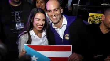 PALING MUDA: Ocasio-Cortez (kiri) membawa bendera Puerto Rico              di kelab malam La Boom di New York kelmarin. — Gambar AFP