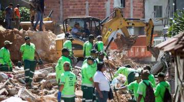 ANGKARA TANAH RUNTUH: Pekerja Syarikat Pembersihan Niteroi membersihkan kawasan yang dijejas tanah runtuh yang berlaku pada awal pagi selepas hujan lebat di bandar Niteroi, Rio de Janeiro kelmarin. — Gambar AFP