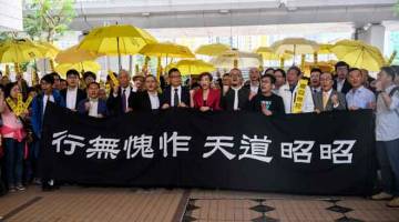 DIBICARA: (Dari kiri, belakang kain rentang) Aktivis pro-demokasi Chung Yiu-wa, Cheung Say-yin, bekas penggubal undang-undang Parti Demokratik Lee Wing-tat, Chu Yiu-ming, Benny Tai, Chan Kin-man, penggubal undang-undang Tanya Chan dan Shiu Ka-chun, dan Timbalan Pengerusi Liga Demokrat Sosial Raphael Wong, berteriak sebelum masuk ke dalam Mahkamah Majistret Kowloon Barat di Hong Kong semalam. — Gambar AFP