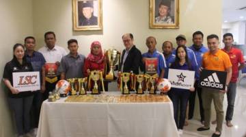 Raymond (enam kiri) menyerahkan piala pusingan kepada Jamilah sambil disaksikan Awang Putrayusrie (empat kiri), barisan exco Pertandingan Bolasepak Liga Lundu 2018 dan wakil penaja dari Lea Sports Centre.